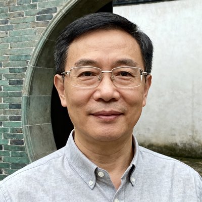 苏州市文旅局王主任的半身近景肖像，他佩戴眼镜穿着浅灰色衬衫，背景是苏州古典园林的月亮门和青砖墙